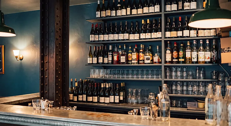 Le comptoir en zinc, une carafe de vin rouge et des verres