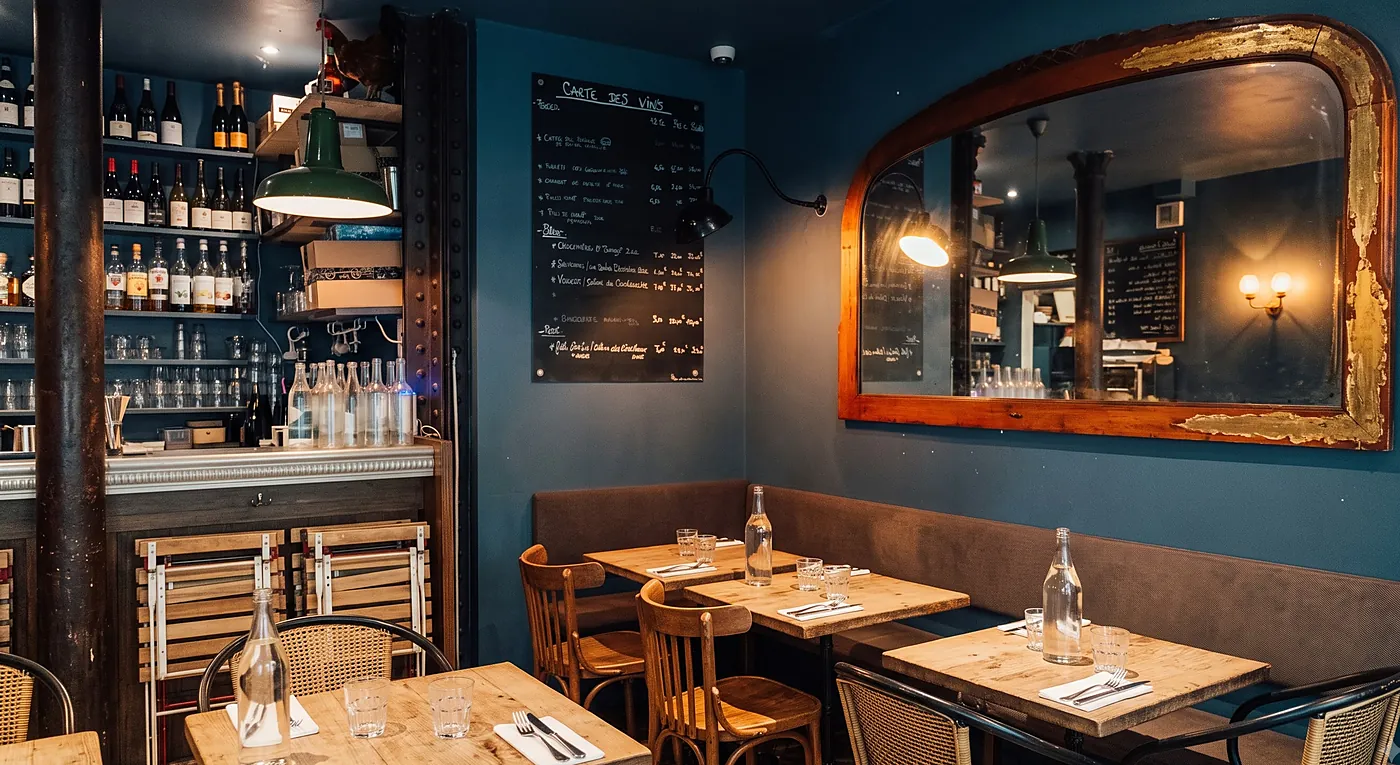 La salle du Tout Petit : murs bleu pétrole, grand miroir doré et ardoise des vins